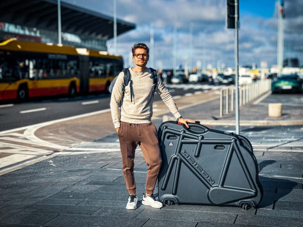 Mężczyzna z walizką rowerową przed terminalem lotniska